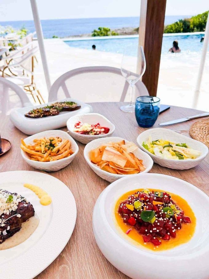 Mesa junto a la playa con postres y aperitivos variados con vistas al océano.