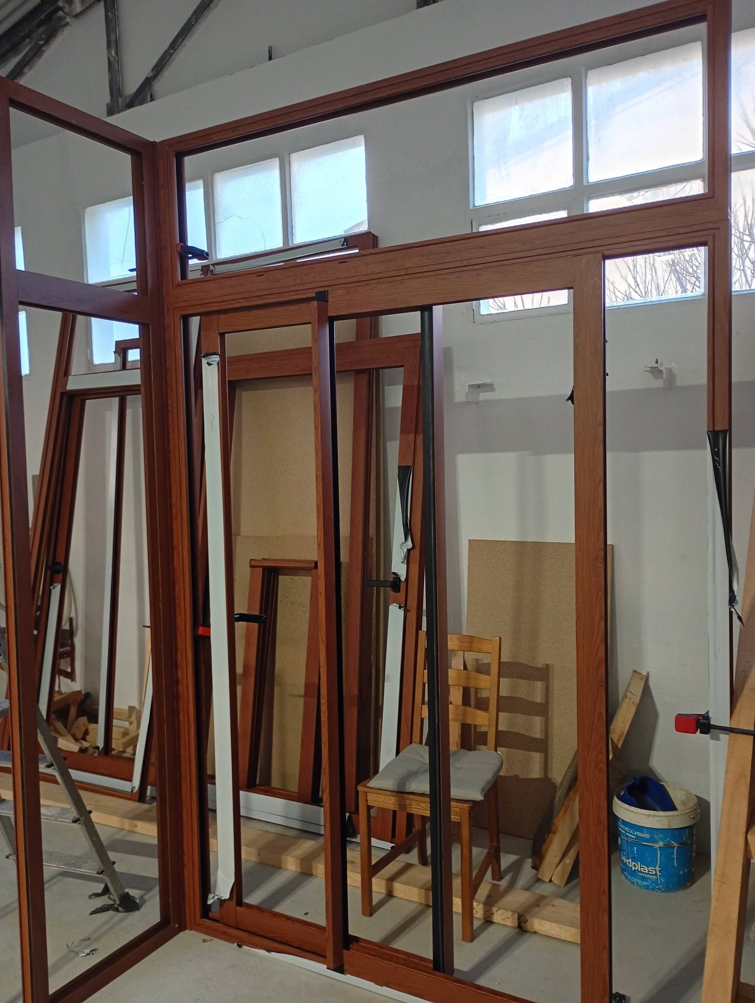 Estructura de madera parcialmente construida en un taller interior, con herramientas y materiales cerca.