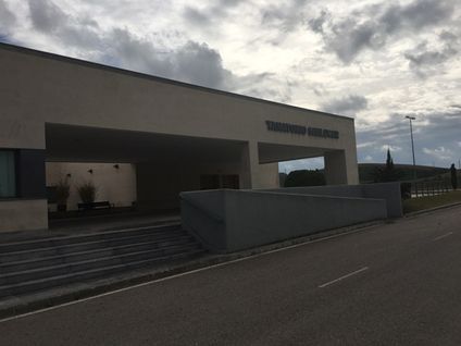 Un gran edificio con escaleras que conducen hasta él está al lado de una carretera.
