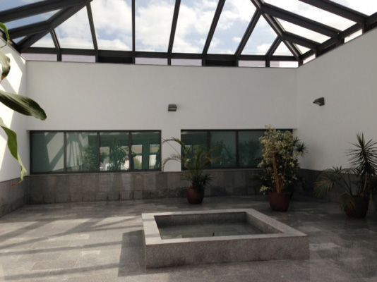 Un edificio con techo de cristal y una fuente cuadrada en el medio.