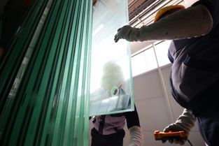 Personen ziehen eine Glasplatte aus mehreren Glasplatten heraus