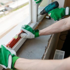 Glaserei Marco Nowak - Personen arbeiten an einem Fensterrahmen mit Wasserwaage