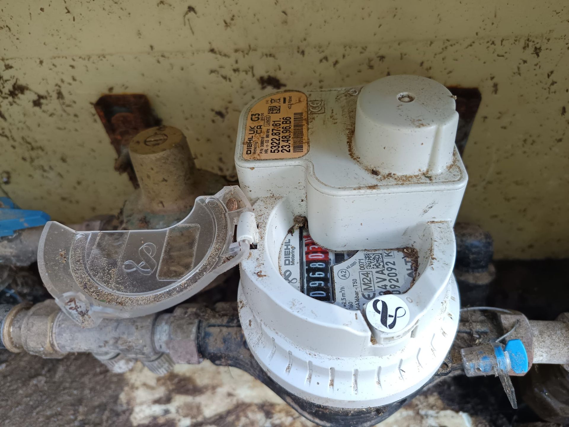 Compteur d'eau avec couvercle en plastique cassé et chiffres visibles.