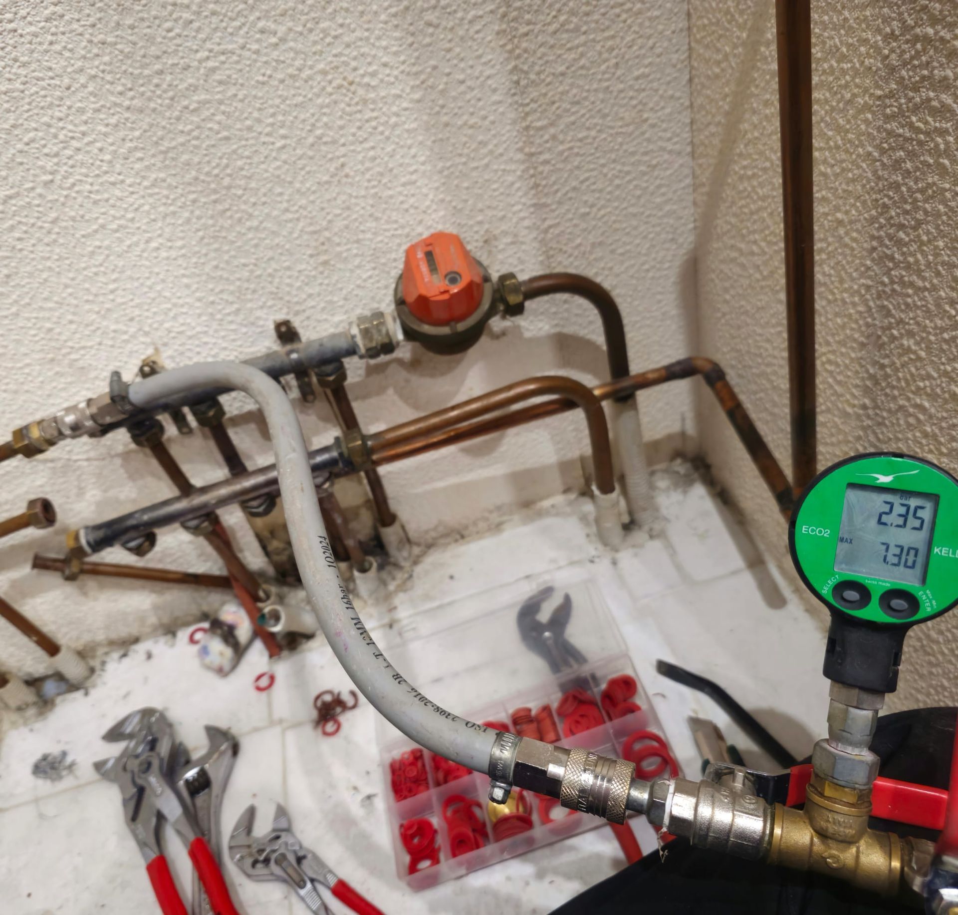 Éléments de plomberie comprenant un manomètre, des clés et des raccords.