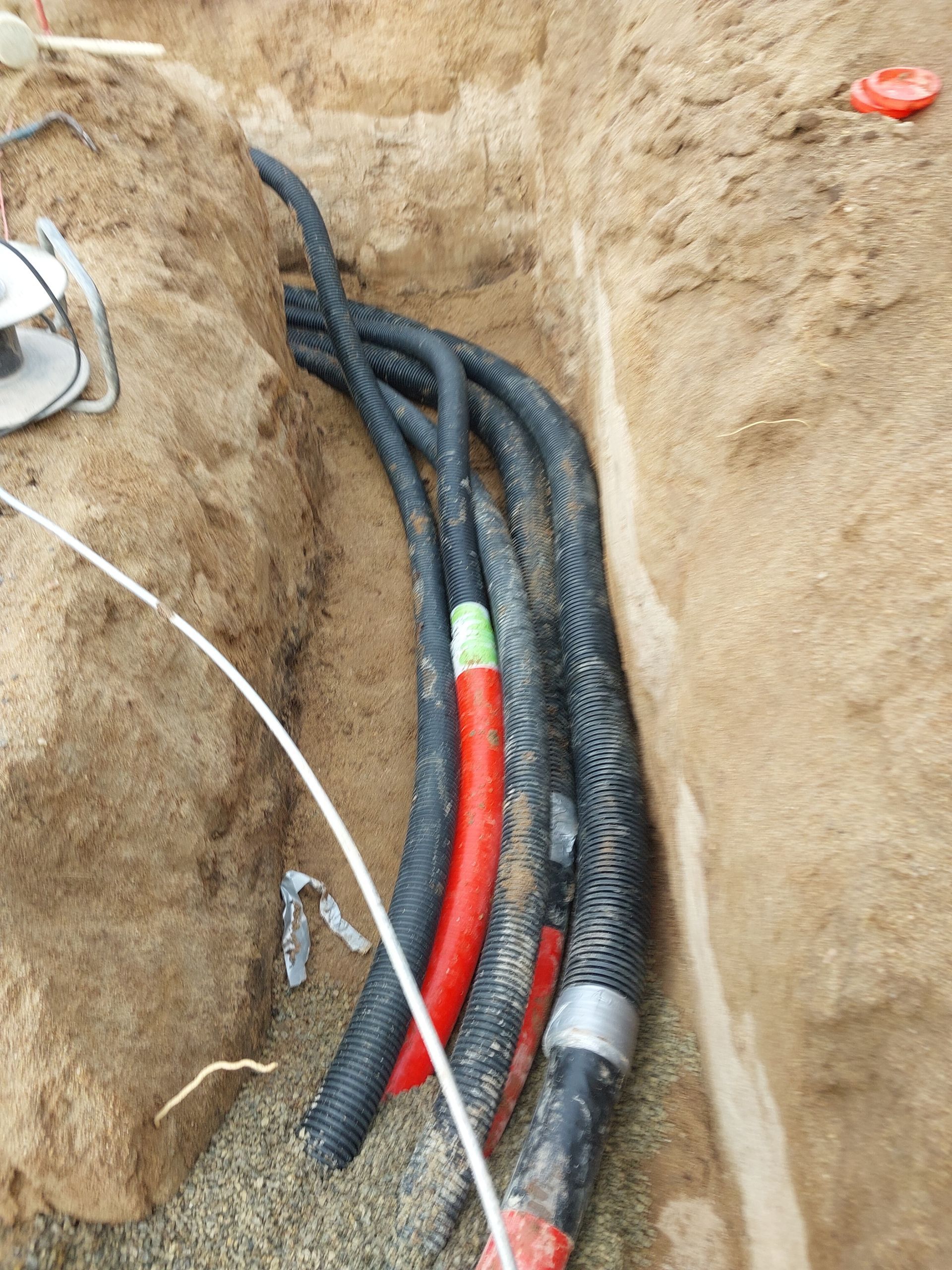 Baustelle: Betonmischer, Walze und Arbeiter neben langen Lagerhallen.