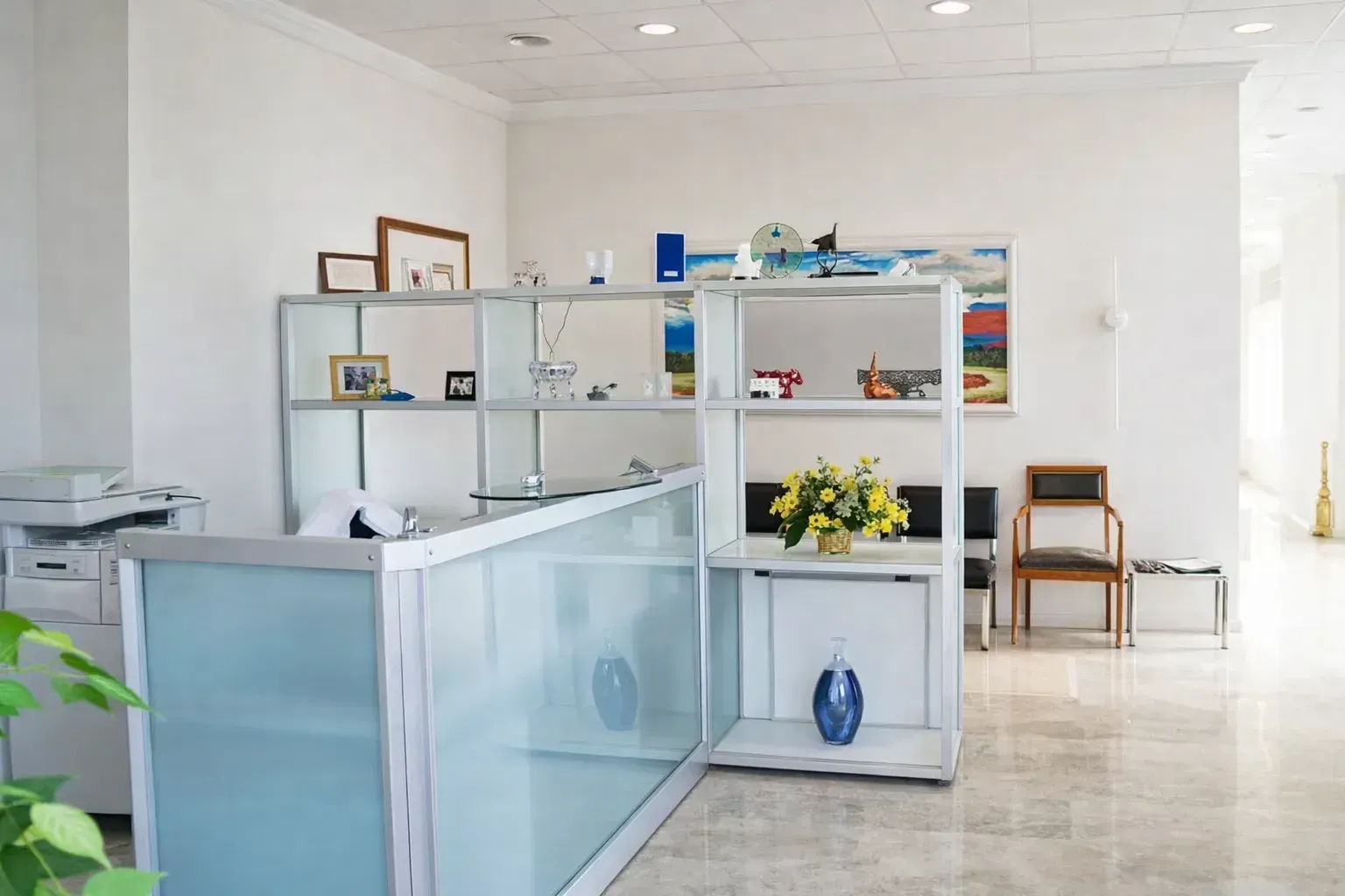 Una luminosa zona de recepción de oficina con un escritorio de cristal esmerilado, estanterías metálicas abiertas