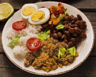 Un bol que contiene arroz blanco, frijoles negros, un huevo duro, farofa