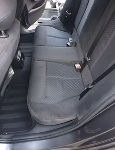 Banquette arrière de voiture sombre avec sièges et ceintures de sécurité noirs.