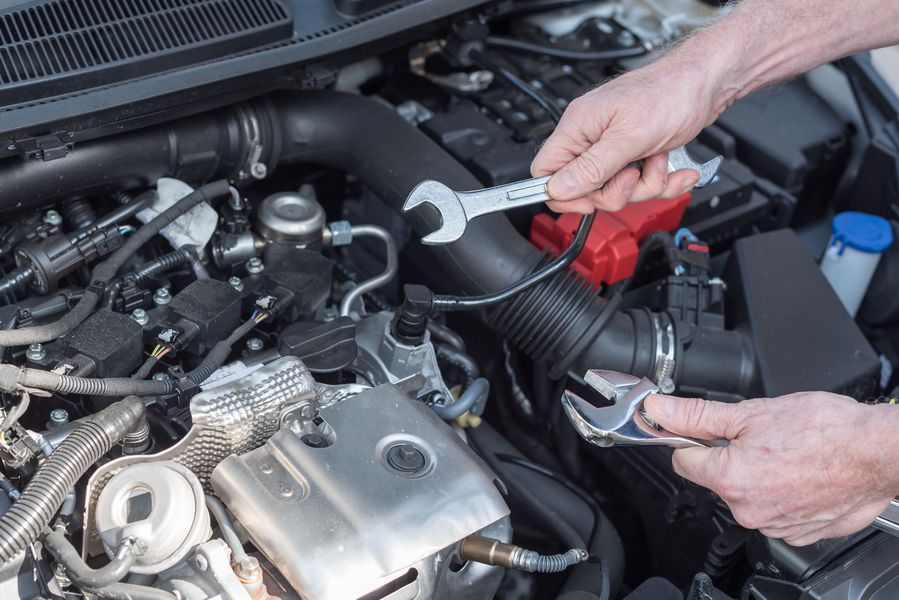 Un garagiste intervenant sur un moteur avec deux clés