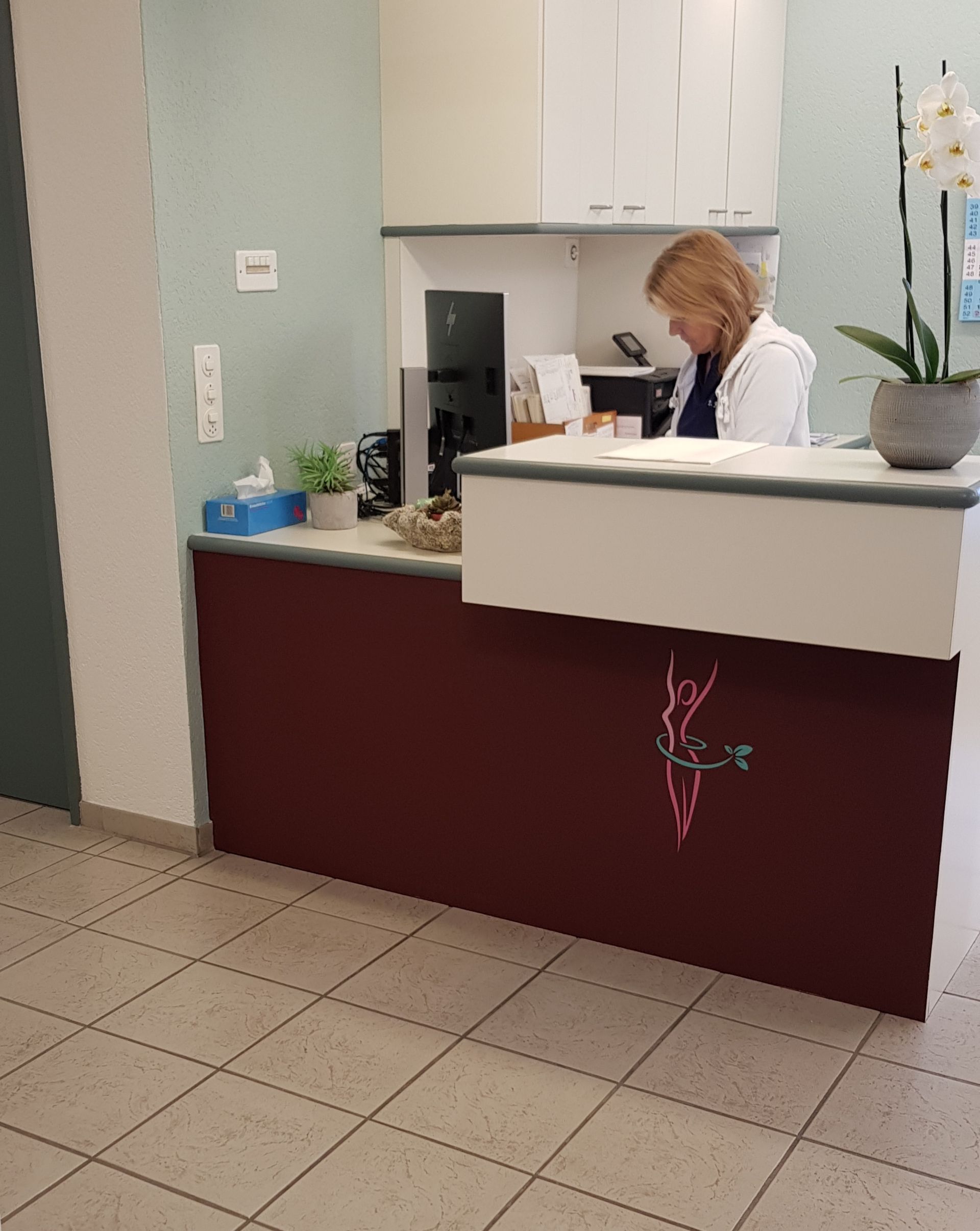 Eine Frau sitzt an einem Empfangstresen in einem Krankenhaus.