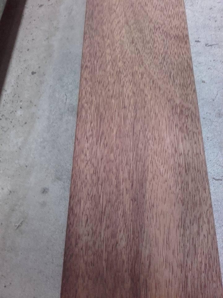 Gros plan d'une planche de bois étroite à côté d'une surface en béton gris à l'extérieur