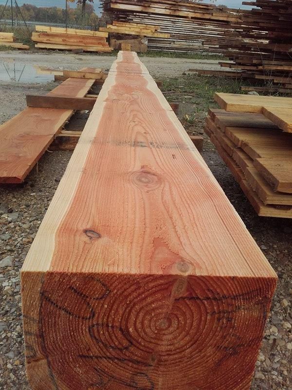 Longue poutre en bois fraîchement coupée, au grain apparent, reposant à l'extérieur dans une scierie.