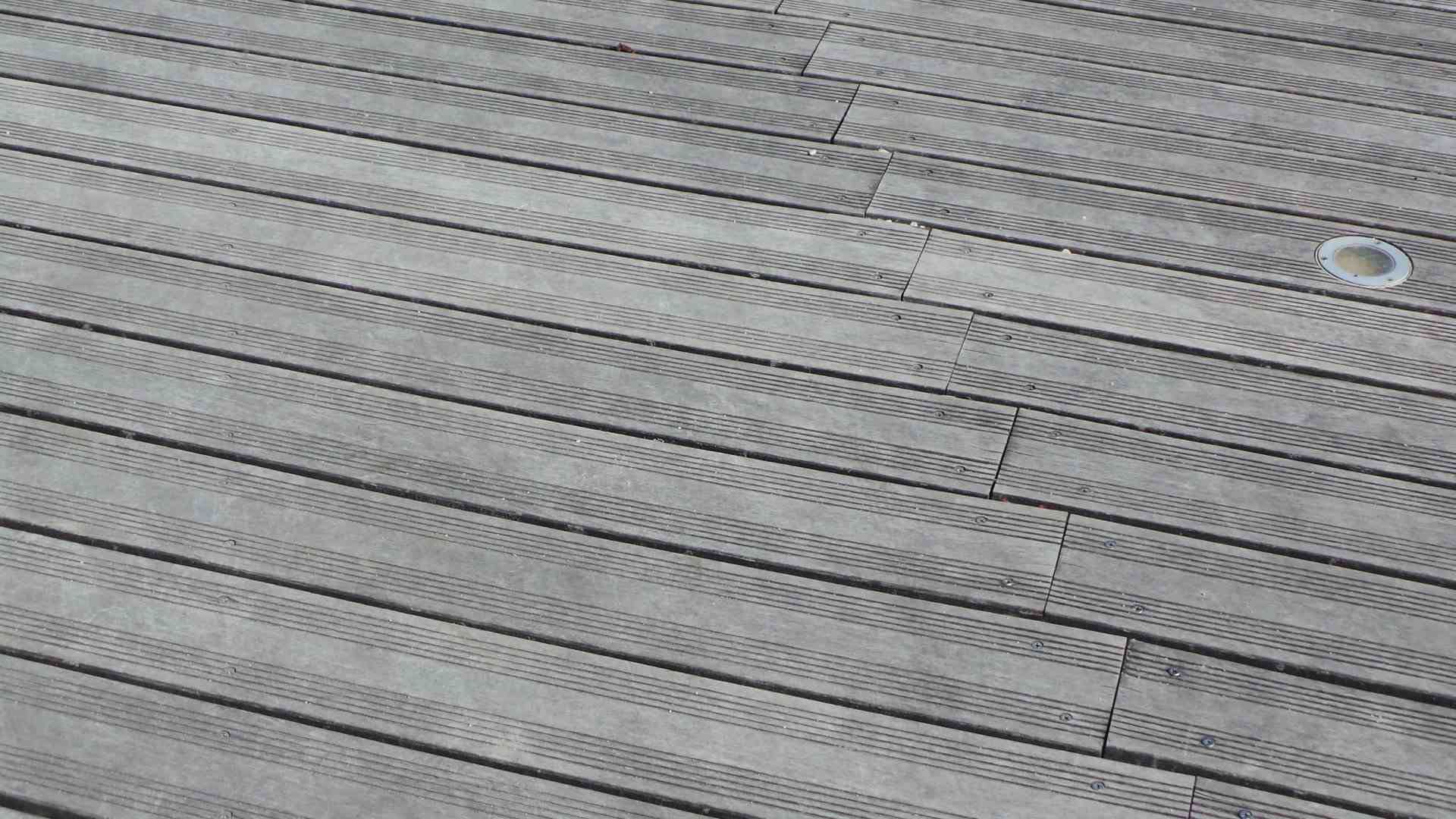 Vue de dessus d'une surface tissée grise texturée avec des lignes cousues en diagonale et un petit anneau blanc près du coin supérieur droit
