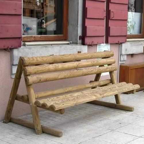 Banc rustique en bois sur un trottoir à côté d'un bâtiment rouge avec des fenêtres