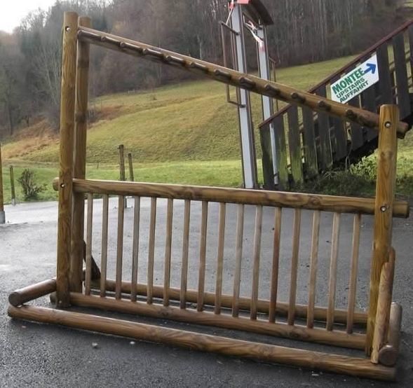 Barrière à bétail en bois bloquant une allée rurale à côté d'un panneau de signalisation sur un versant pluvieux