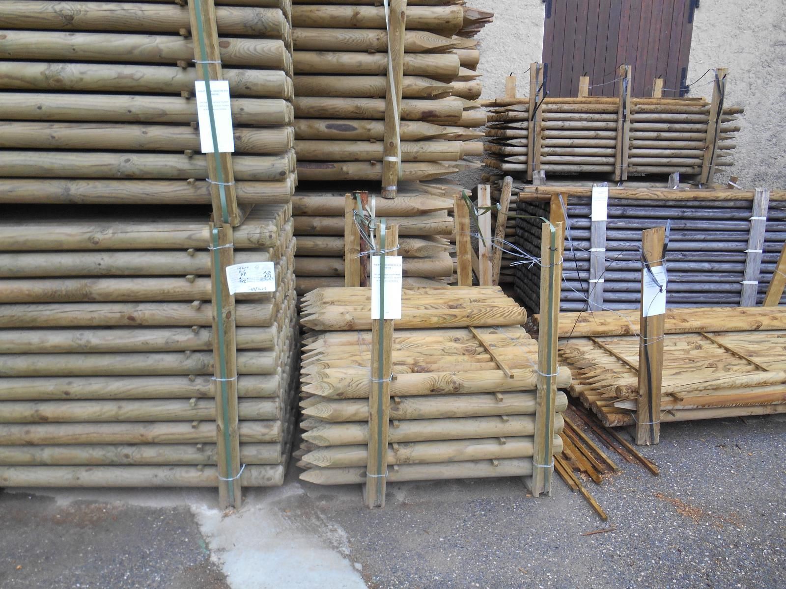 Bois d'œuvre et planches de bois empilés et stockés à l'extérieur, dans une cour, avec des étiquettes sur les piles.