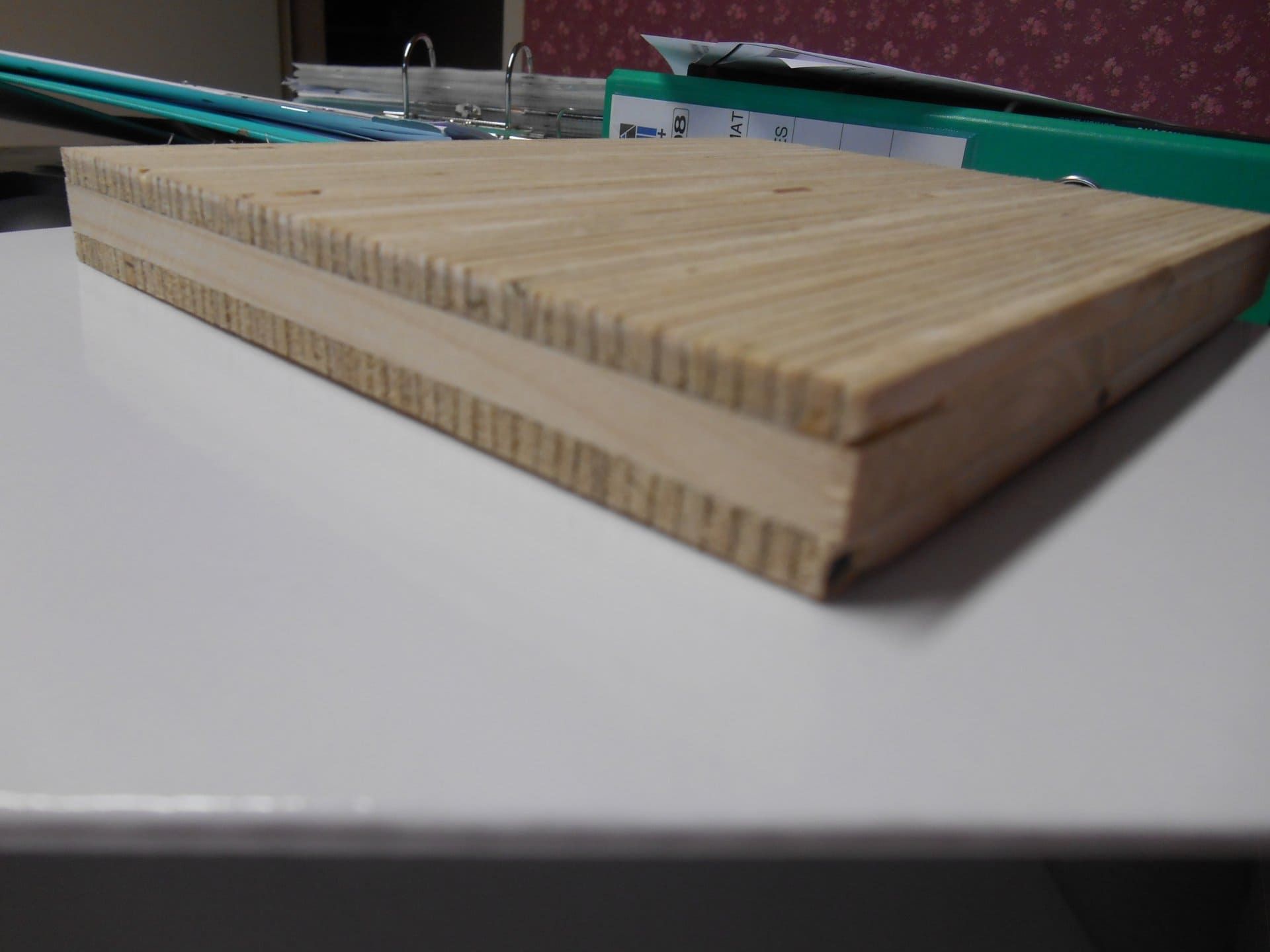 Pile de lattes de bois clair sur une table blanche, vue en contre-plongée.