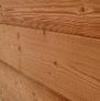 Gros plan sur un mur en planches de bois brun chaud, laissant apparaître le grain et les nœuds.