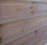 Gros plan sur des planches de bois clair montrant les nœuds et le grain.