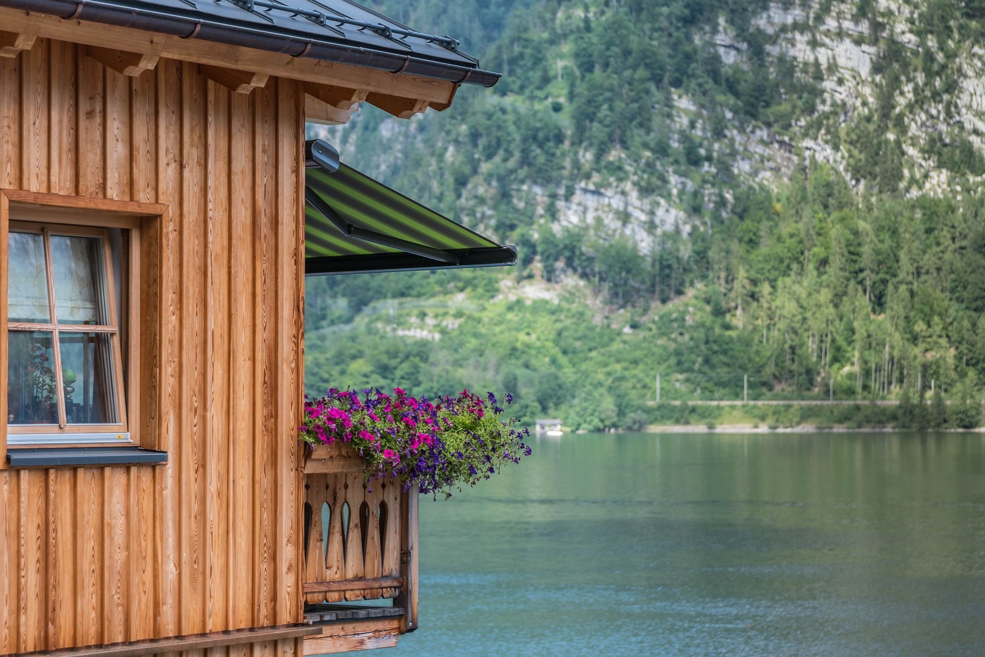 Chalet en bois au bord d'un lac paisible et verdoyant, avec balcon fleuri.