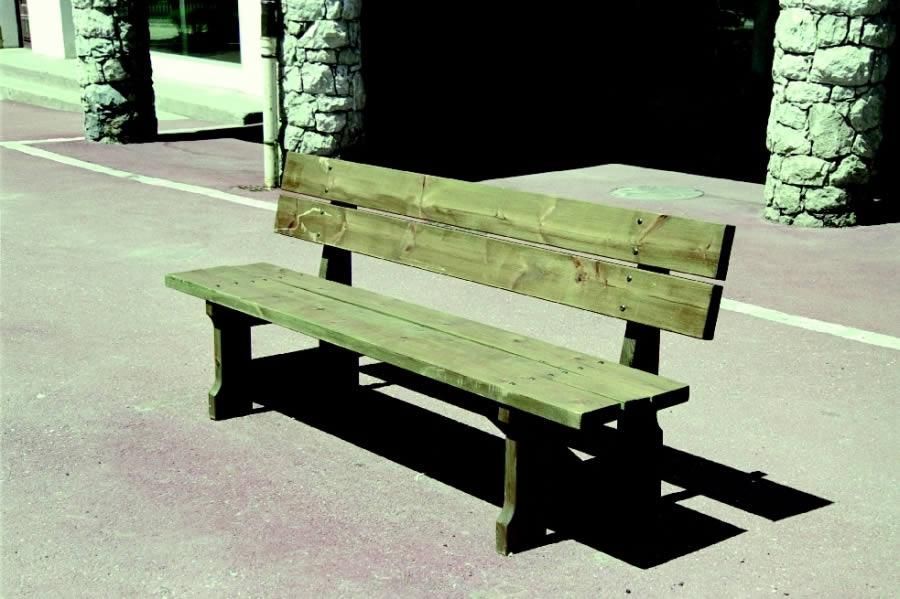 Banc en bois sur un trottoir ensoleillé près de colonnes de pierre, projetant une longue ombre