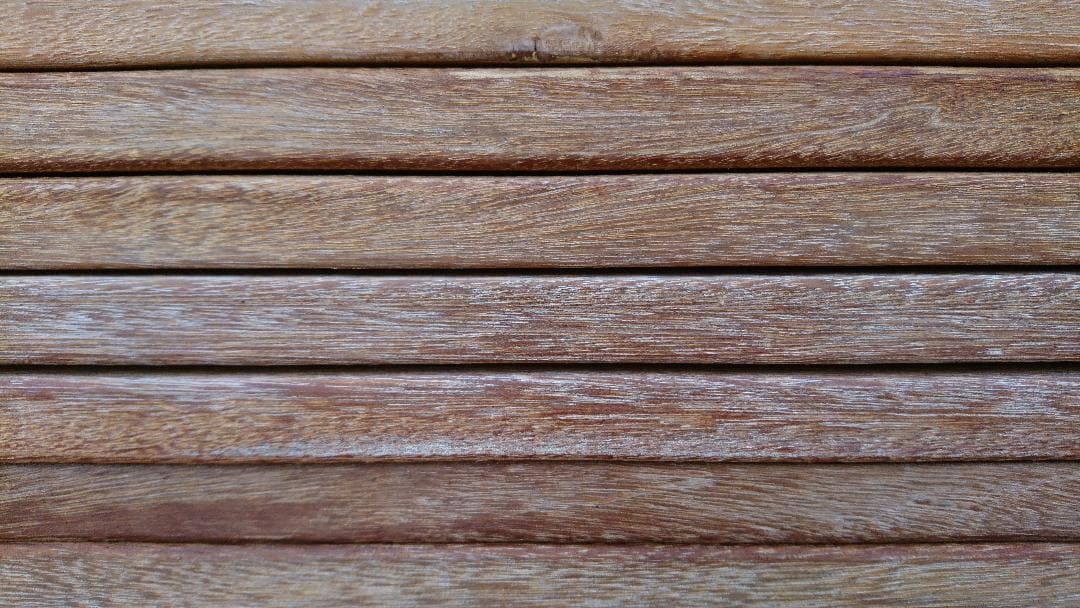 Planches de bois brun vieilli, à la peinture blanche écaillée, disposées horizontalement