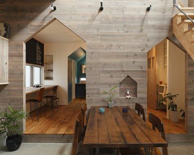 Salle à manger moderne avec alcôves en bois en forme de maison, longue table et accents de bois chaleureux.