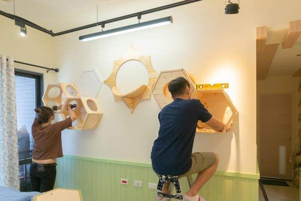Deux personnes fixent des étagères hexagonales en bois sur un mur