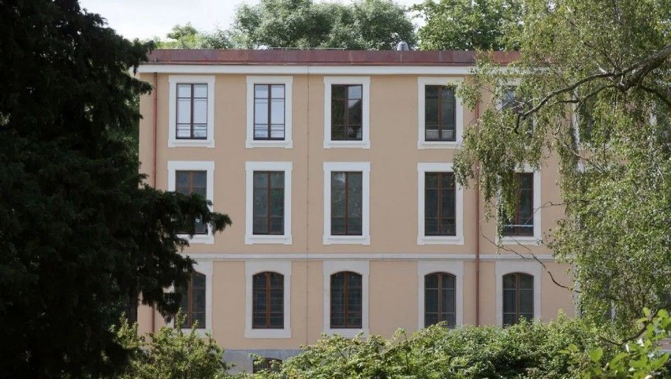 Un grand bâtiment avec beaucoup de fenêtres est entouré d'arbres