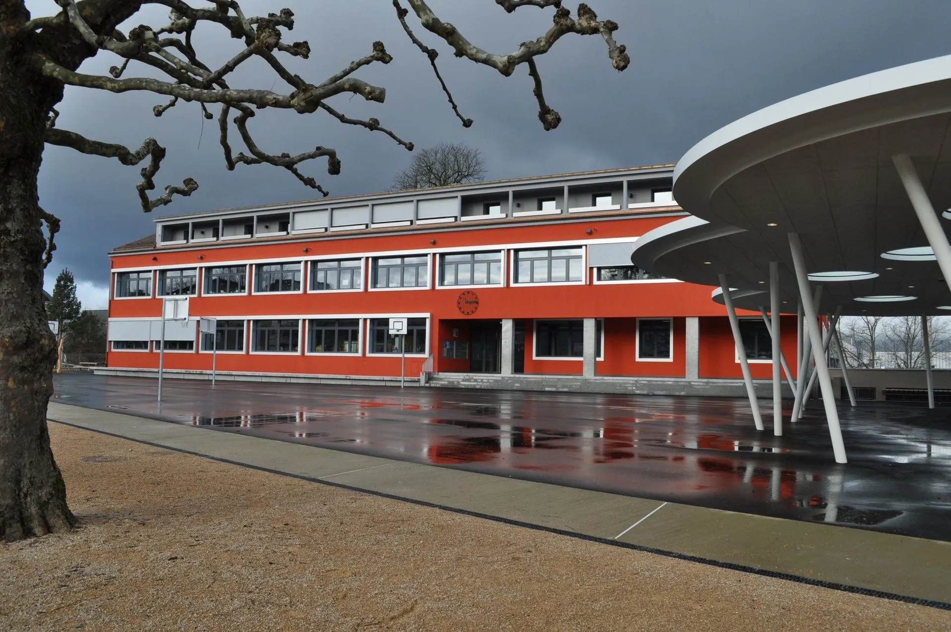 Un grand bâtiment rouge avec un arbre devant