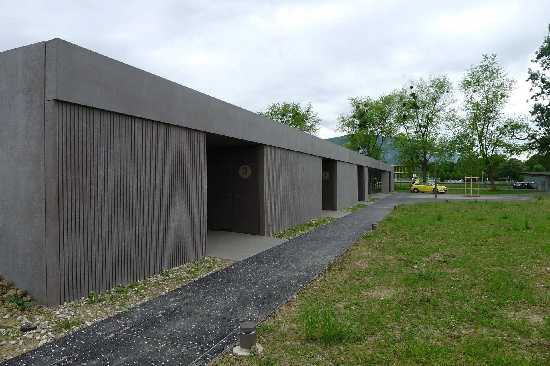 Une voiture jaune est garée devant un immeuble avec des portes coulissantes.