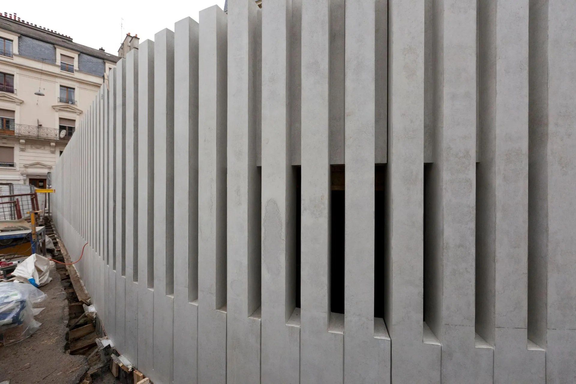 Une clôture en béton est en cours de construction devant un bâtiment.