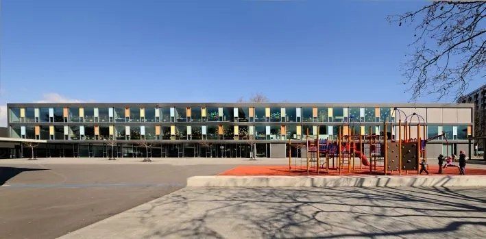 Un grand bâtiment avec une aire de jeux devant.