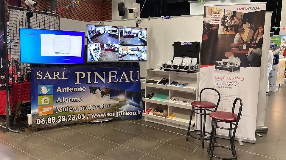 Stand d'exposition intérieur avec écrans de télévision, étagères et une chaise.