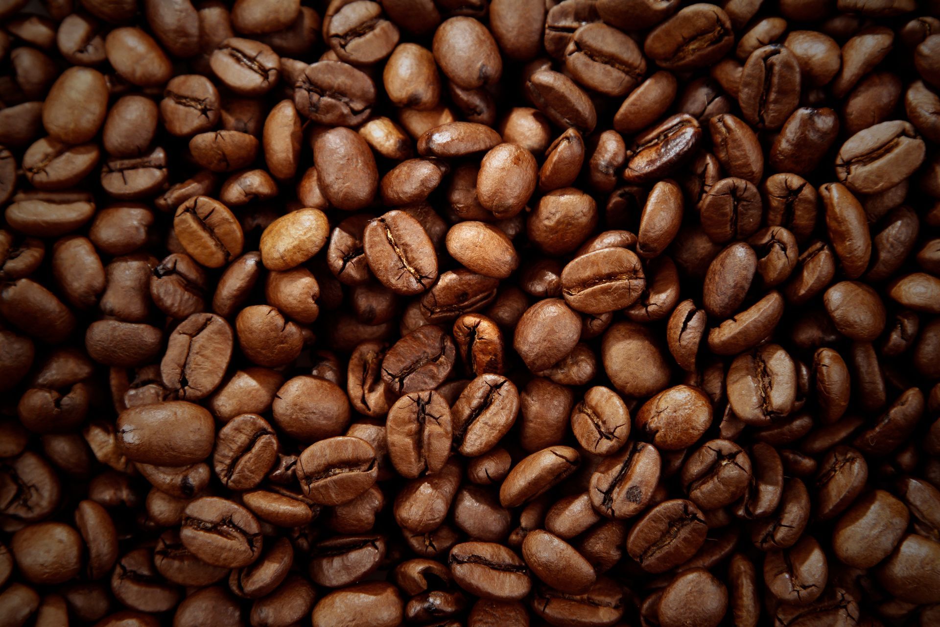 Une vue dense, prise du dessus, de grains de café bruns torréfiés remplissant tout le cadre.