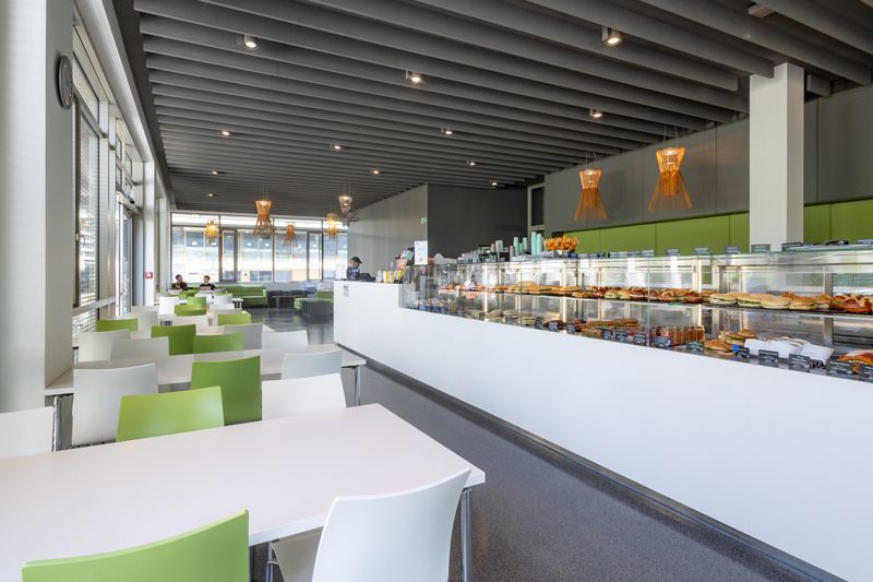 Ein Restaurant mit Tischen und Stühlen und einer langen Theke voller Essen.