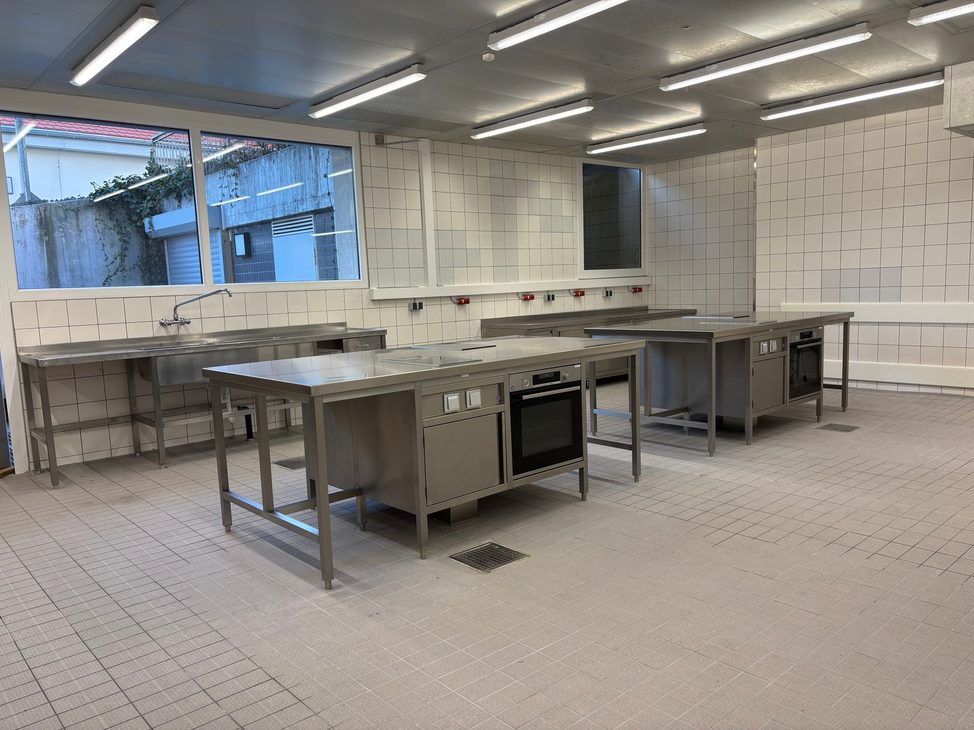 Eine große leere Küche mit Tischen und Öfen aus Edelstahl.