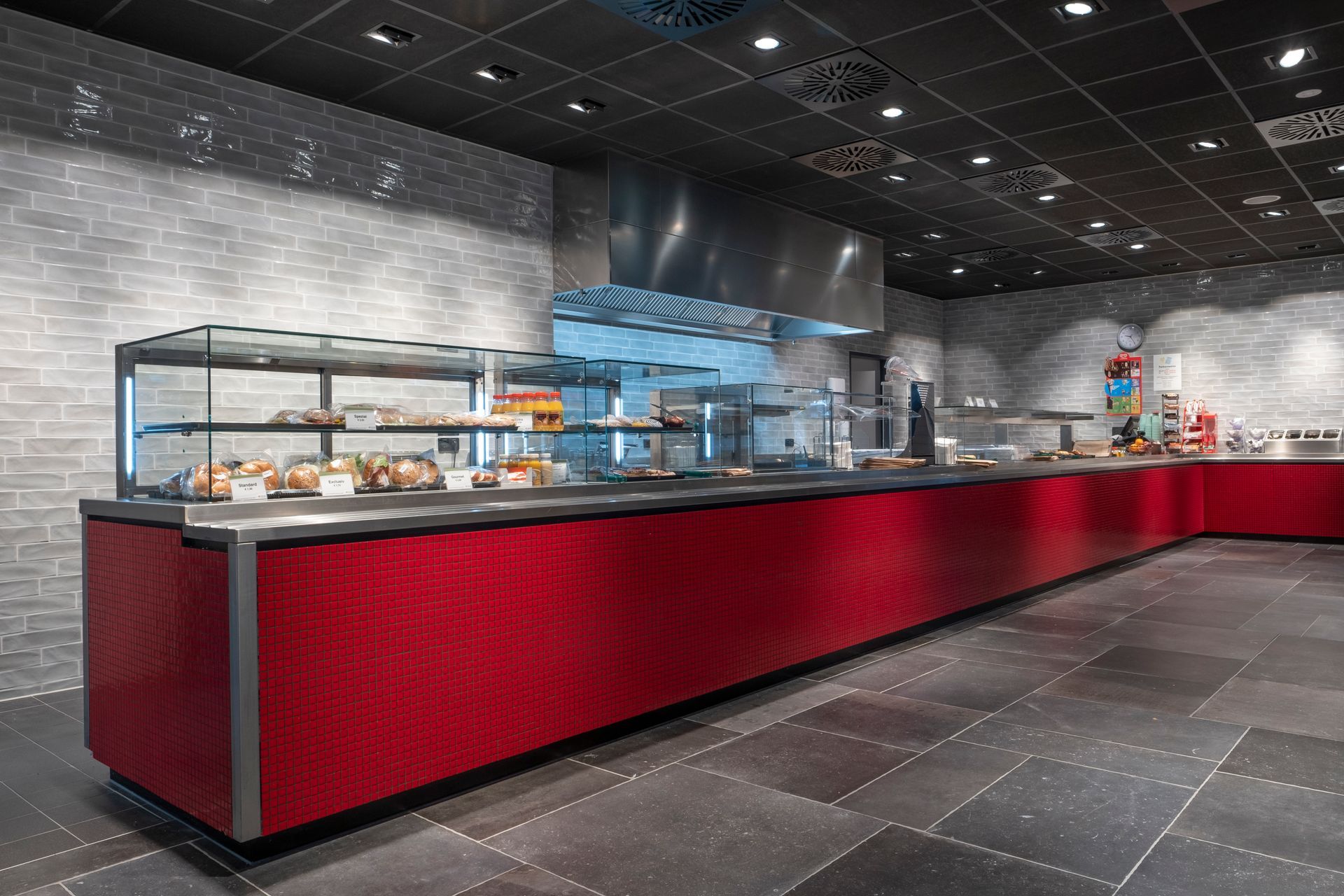 Eine lange rote Theke in einem Restaurant mit einer Arbeitsplatte aus Edelstahl.