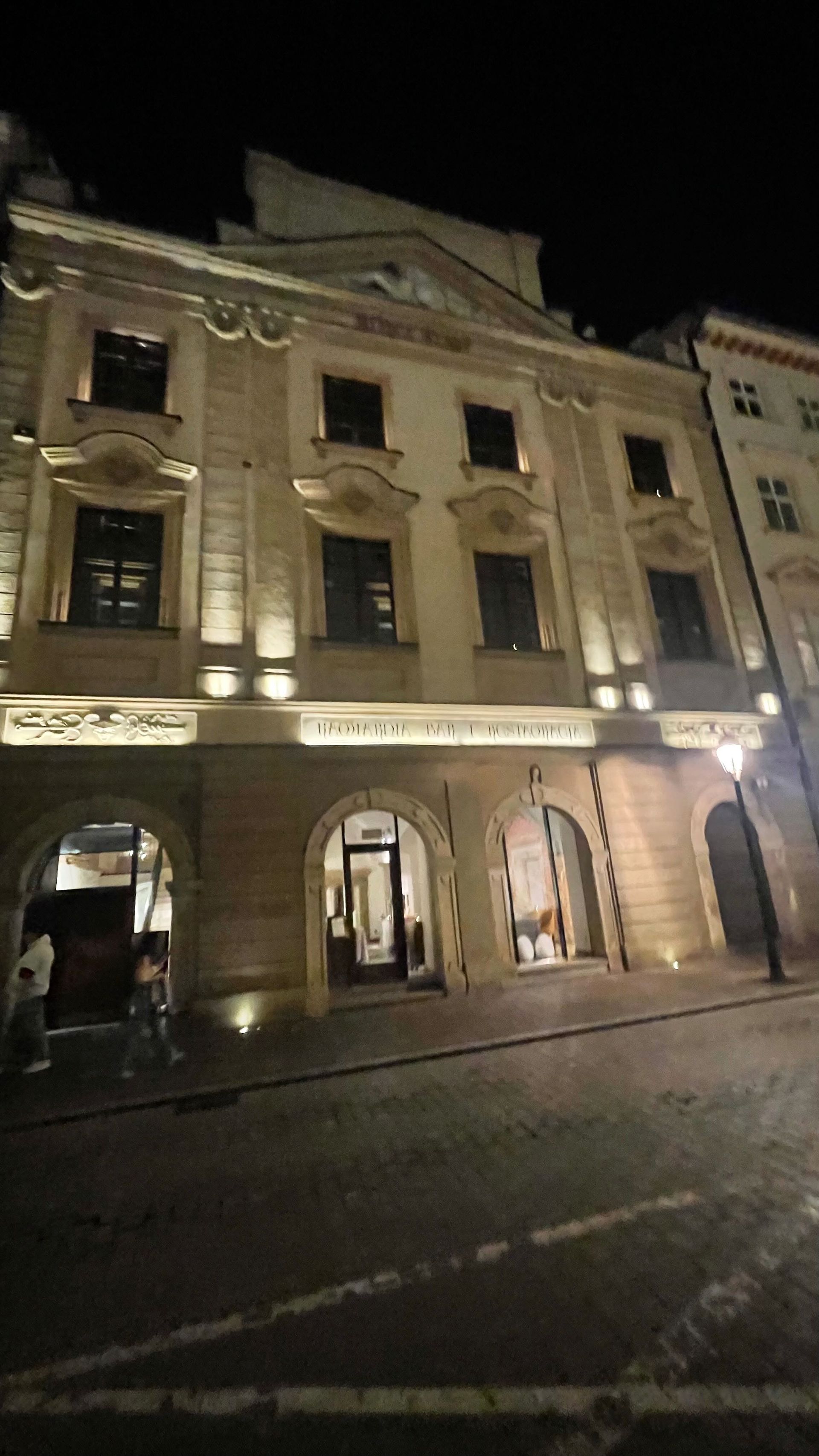 Elegant building facade at night with illuminated arches and windows.