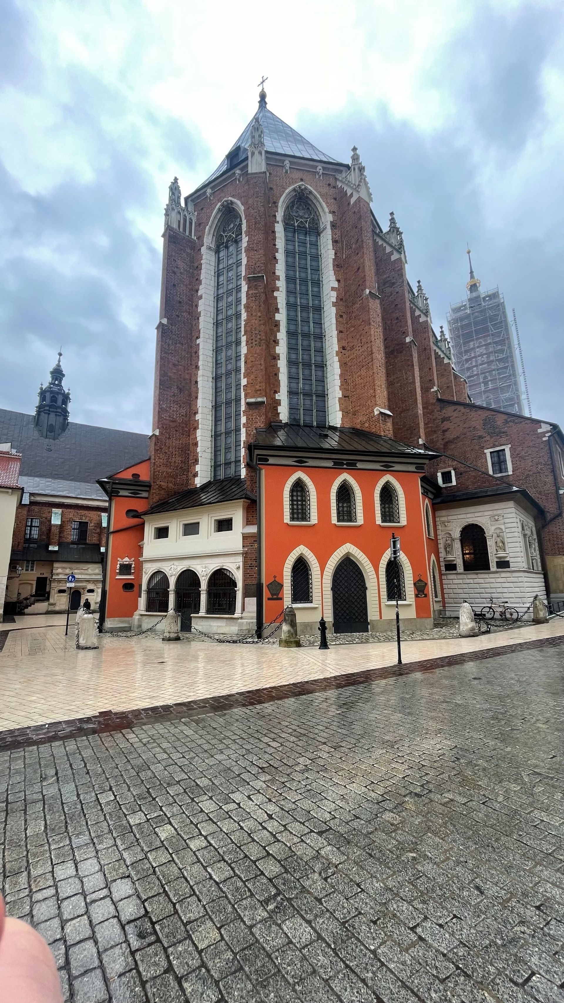 Brick church building with tall arched windows, orange accents, and cobblestone street.