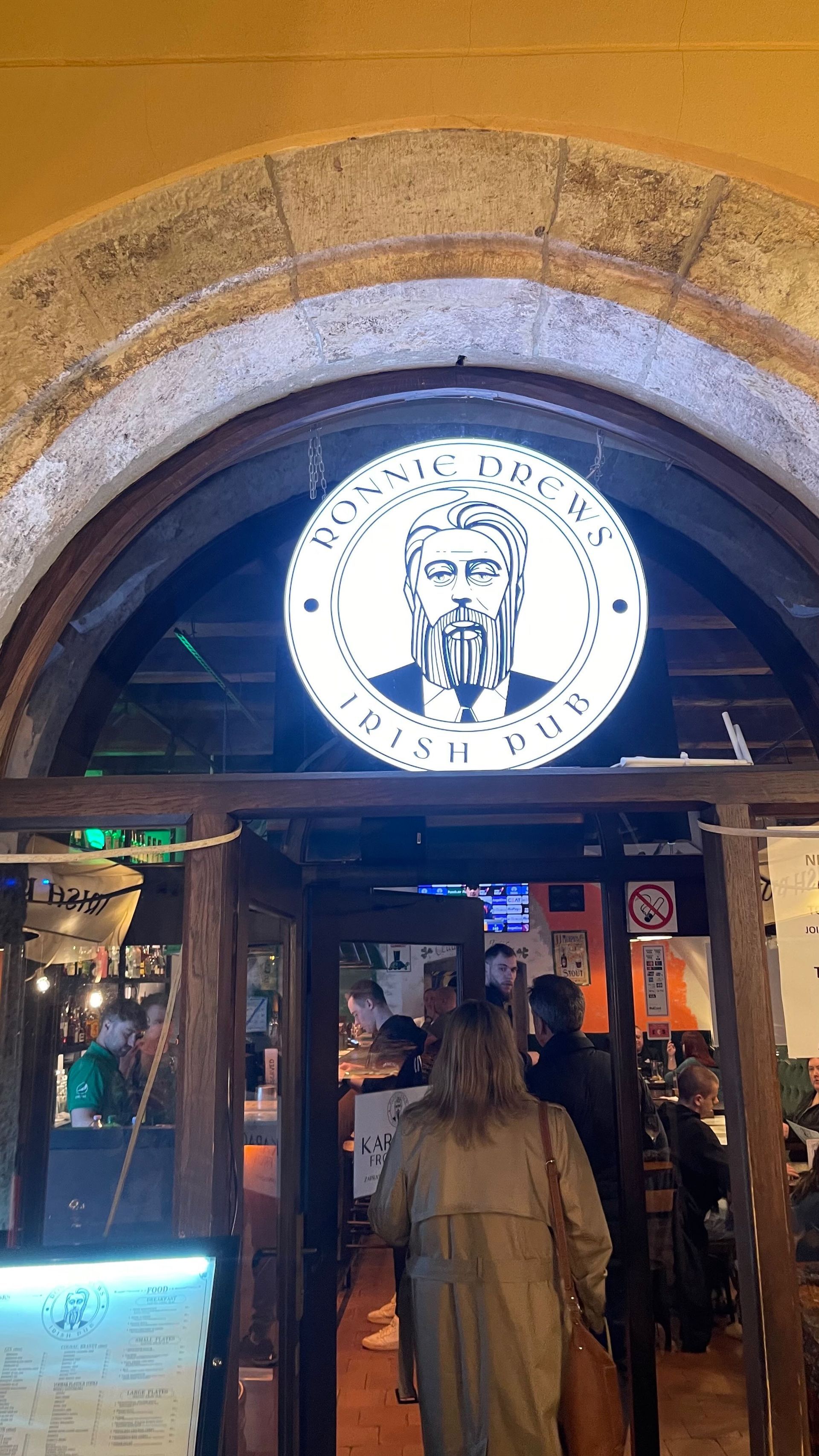 Sign above an Irish pub entrance; a person enters.