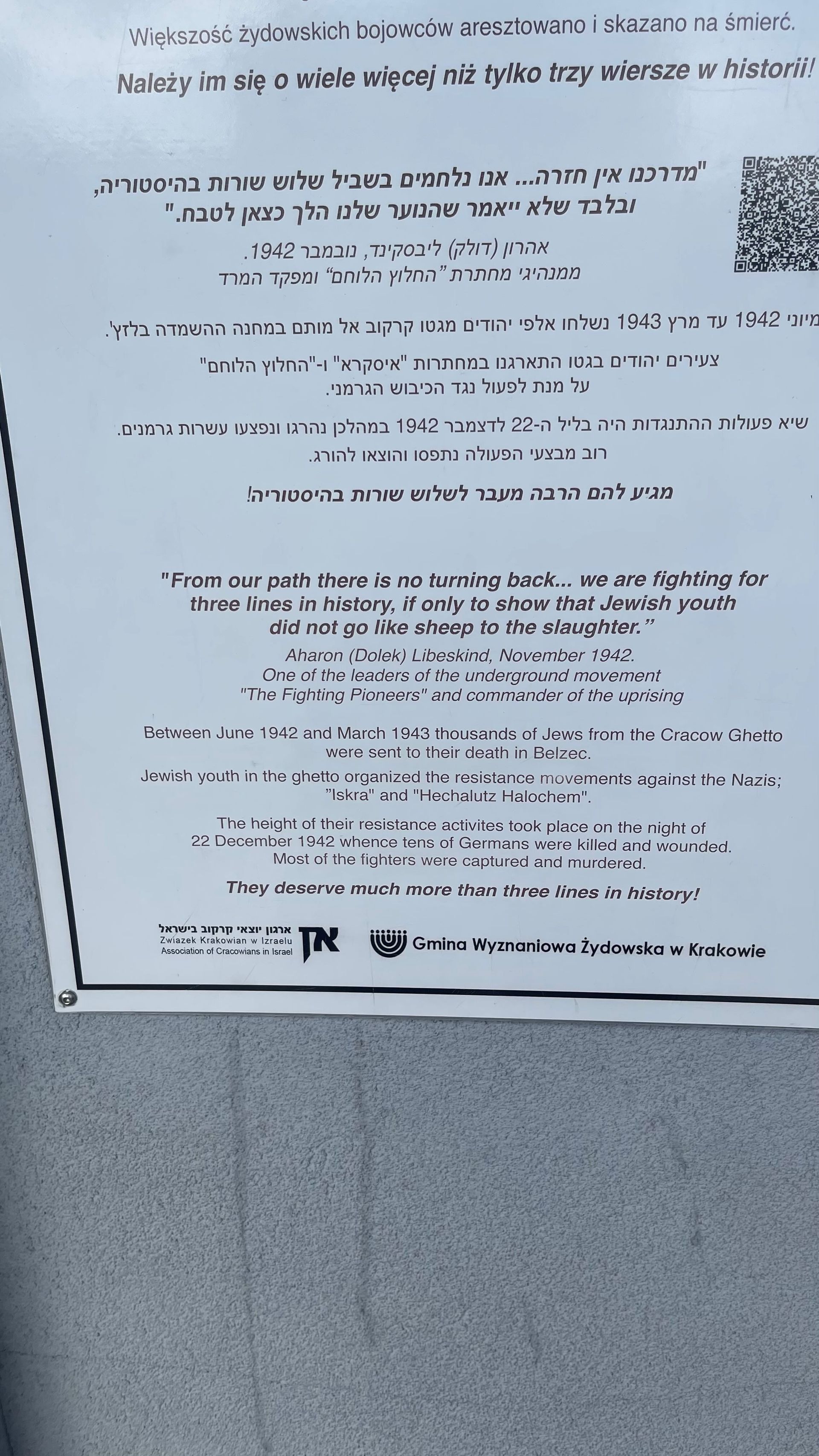 White document with text and QR code on a light gray surface, possibly outdoors.