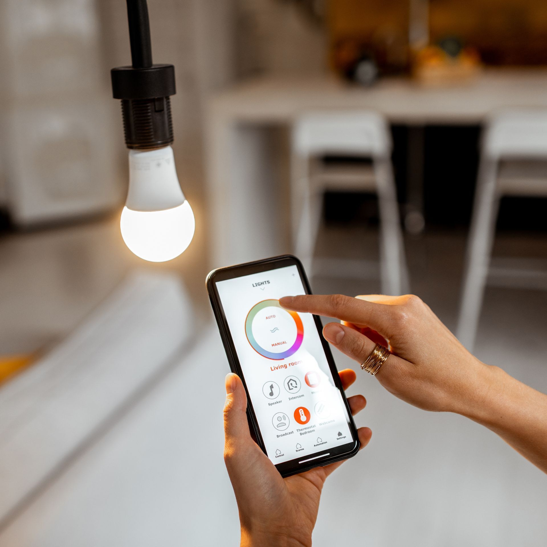 Una persona está usando un teléfono inteligente para controlar una bombilla.
