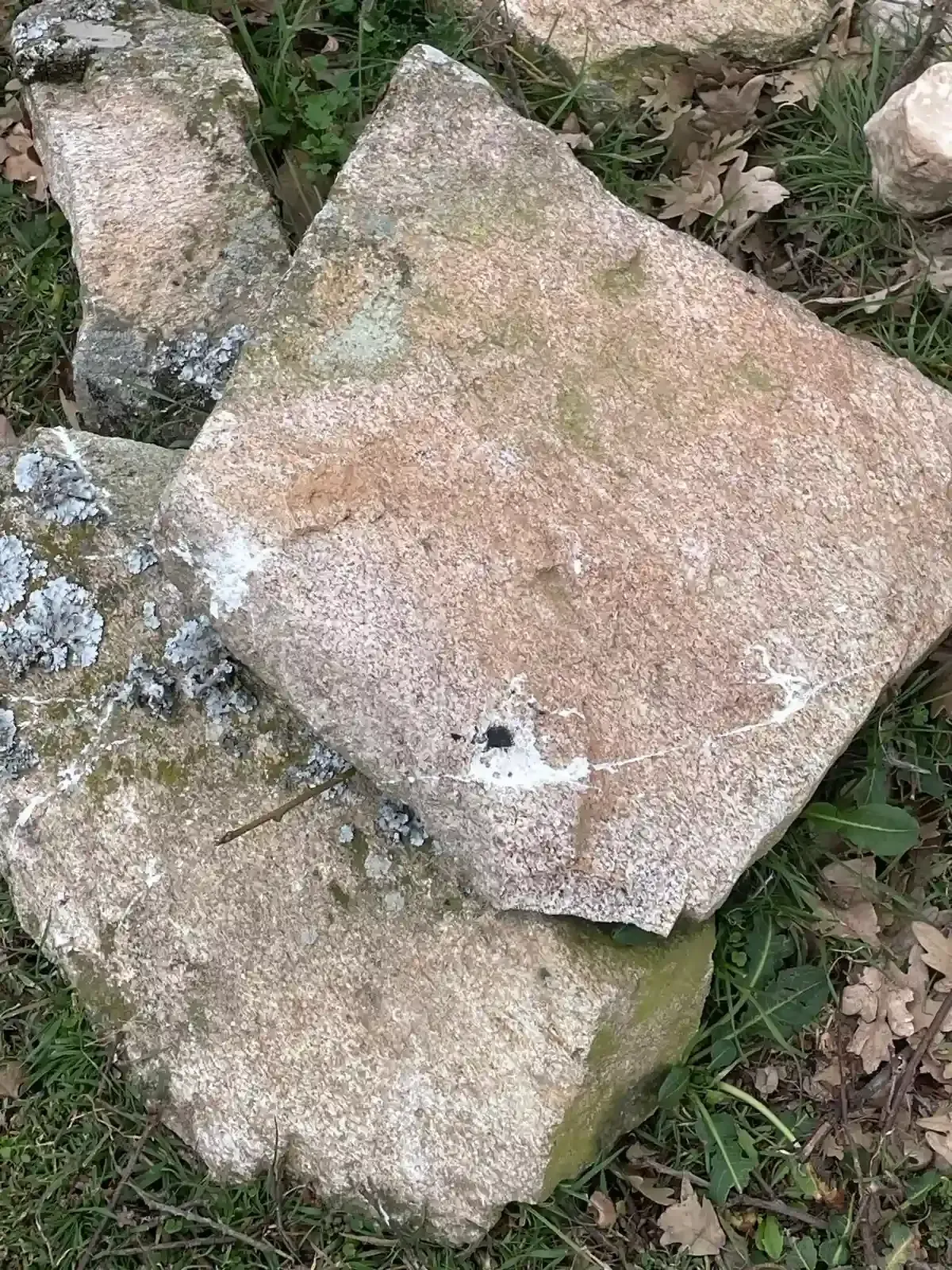 Baldosas de piedra tosca y rocas esparcidas por el suelo con parches de hierba a su alrededor.
