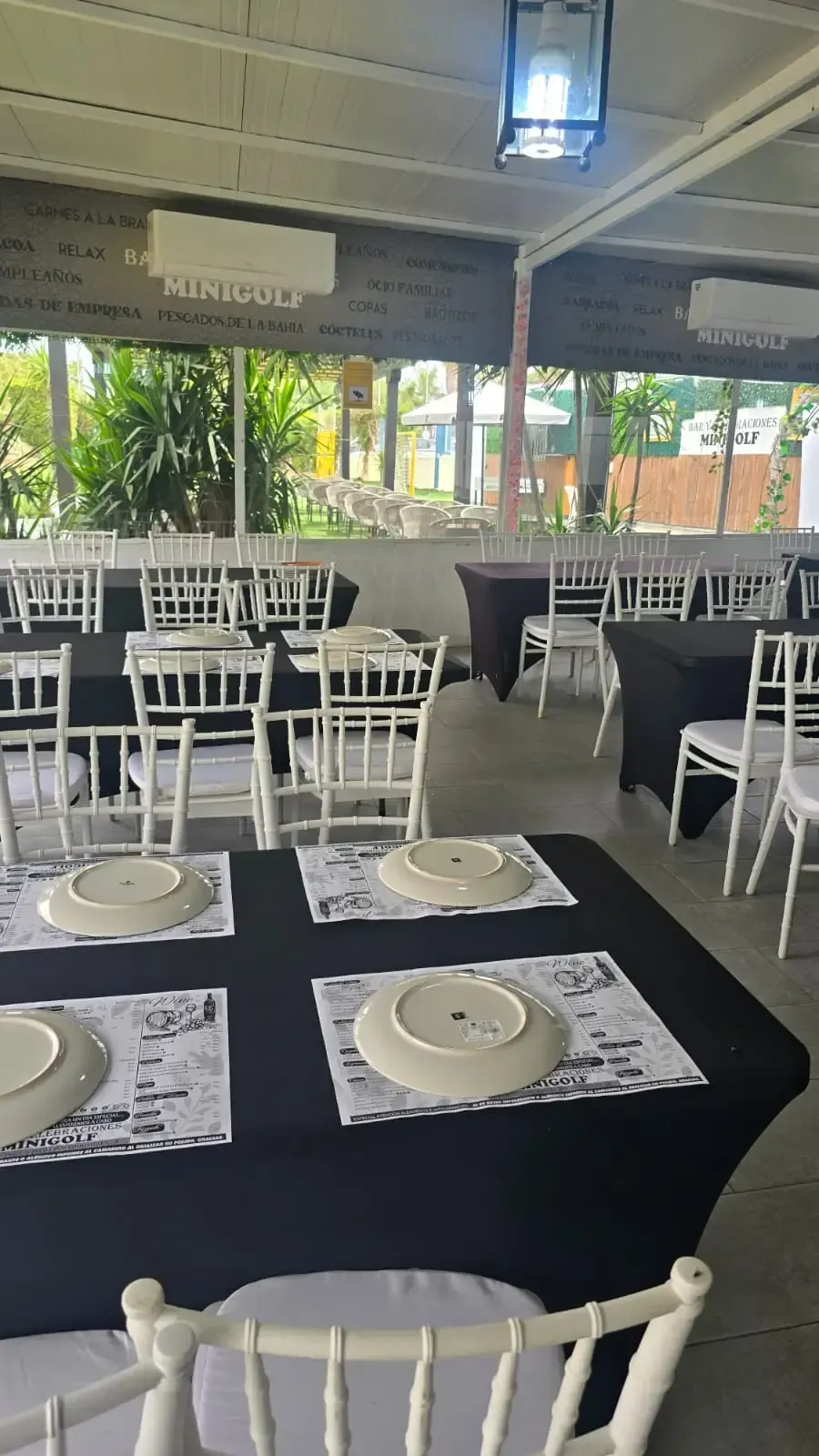 Un área de patio con mesas y sillas bajo una pérgola.
