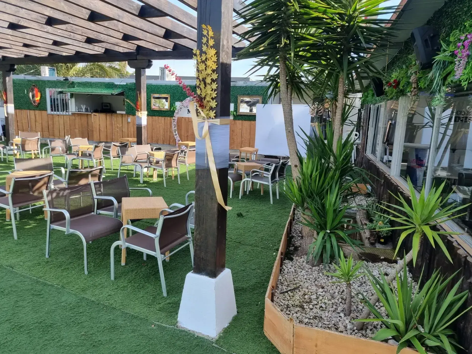 Un área de patio con mesas y sillas bajo una pérgola.