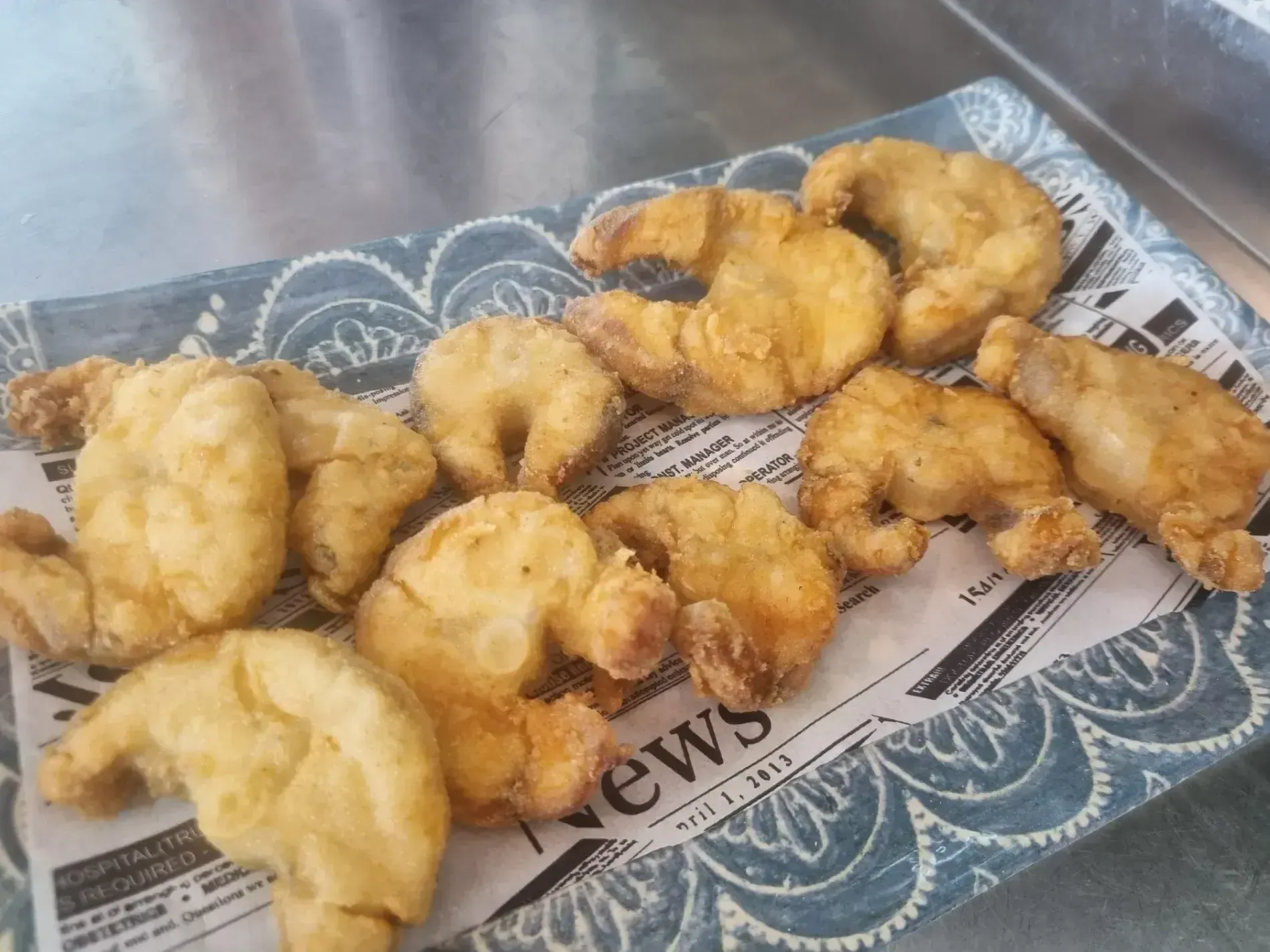 Un plato de camarones fritos está encima de un periódico.