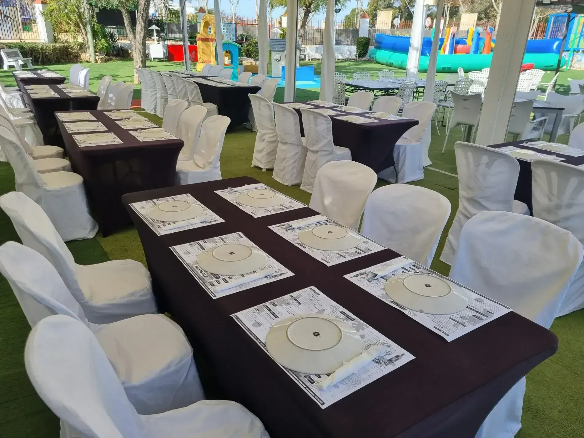 Una fila de mesas y sillas preparadas para una fiesta.