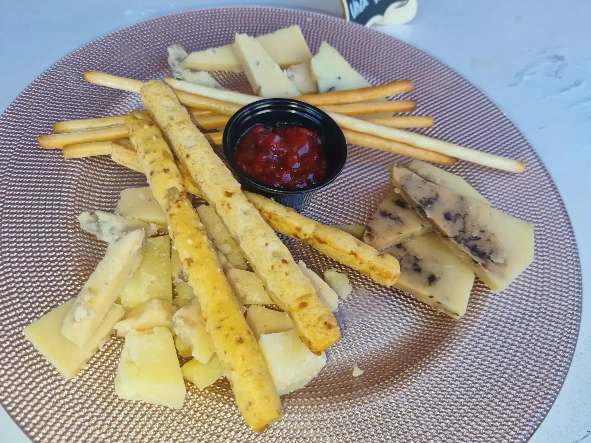 Un plato de queso y galletas con un tazón pequeño de ketchup