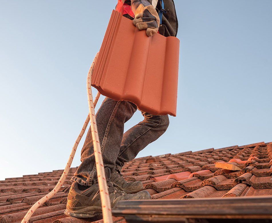 Homme portant une tuile neuve sur un toit